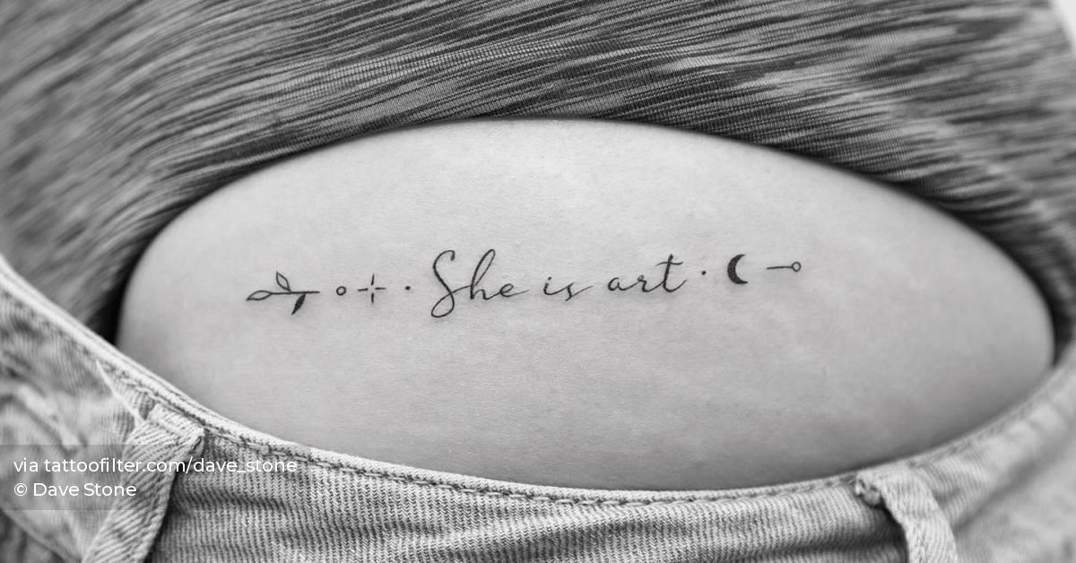 "She is art" lettering tattoo handwritten on the hip.