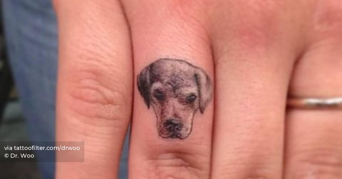 Tiny dog portrait tattoo located on the the finger.
