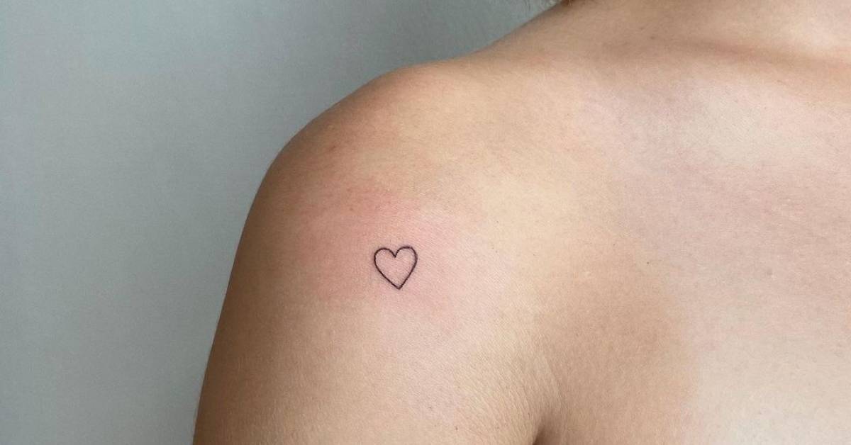Tiny minimalistic heart tattoo located on the shoulder.