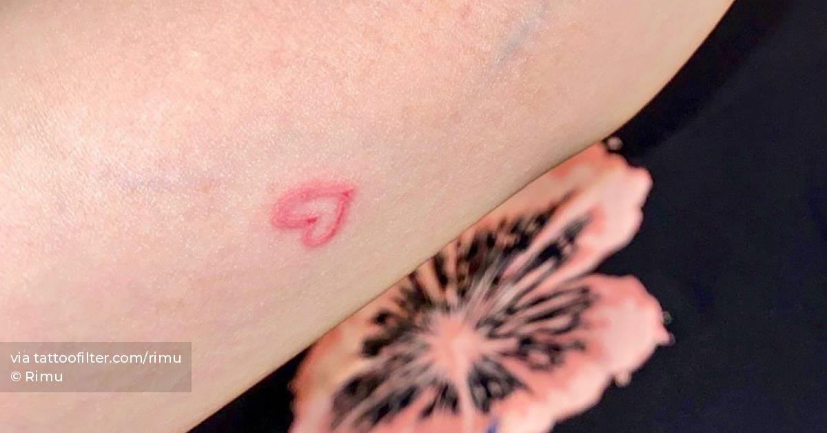 Tiny red heart tattoo located on the inner forearm.
