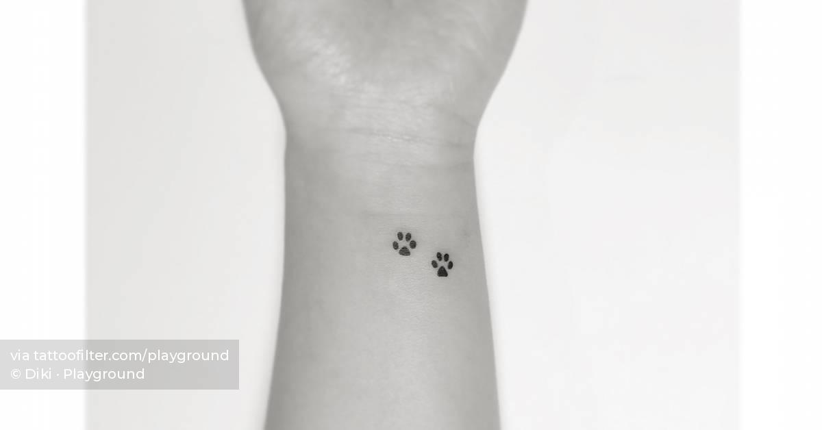 Tiny minimalistic dog paws tattooed on the wrist.