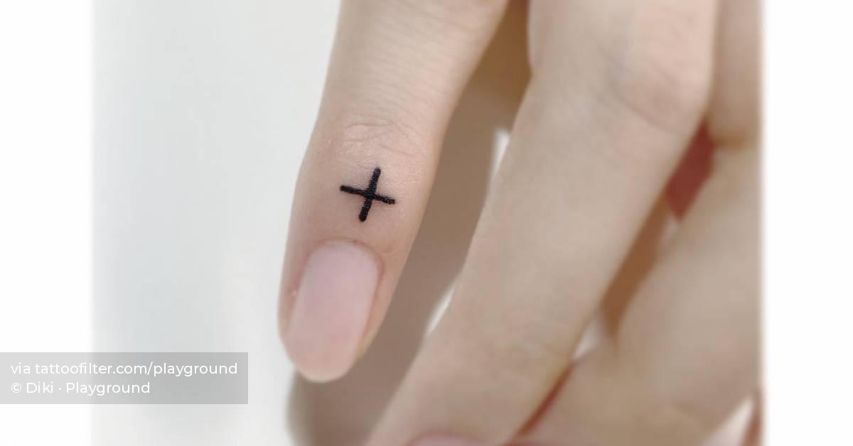 Tiny plus sign tattoo located on the finger.