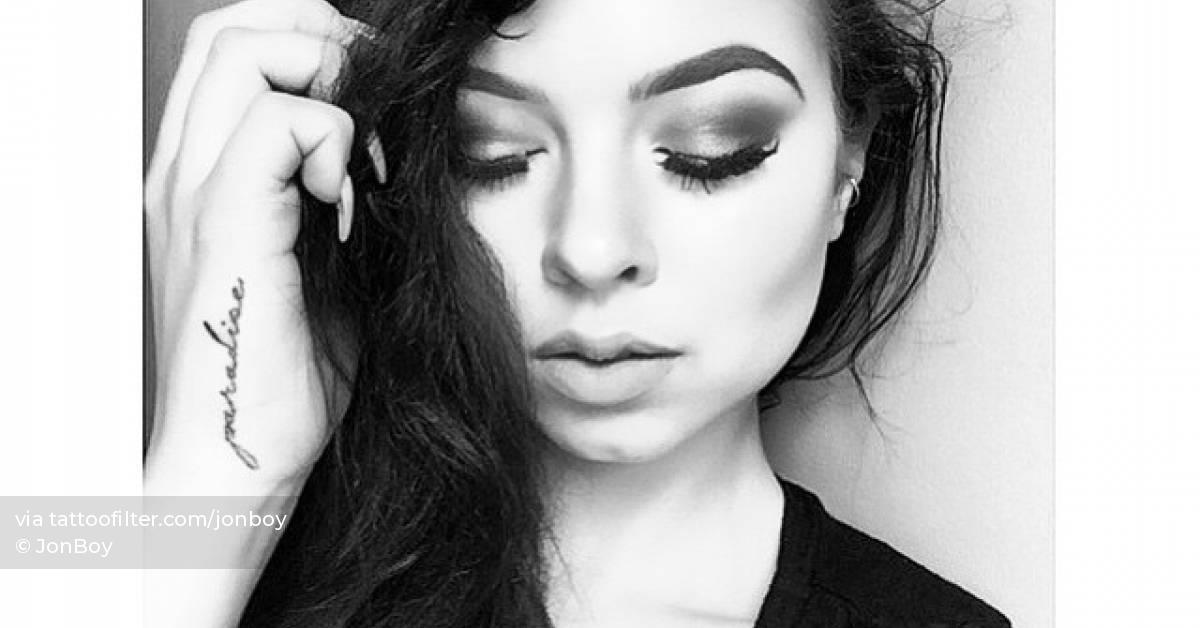 Tattoo of the word "paradise" handwritten on the hand.