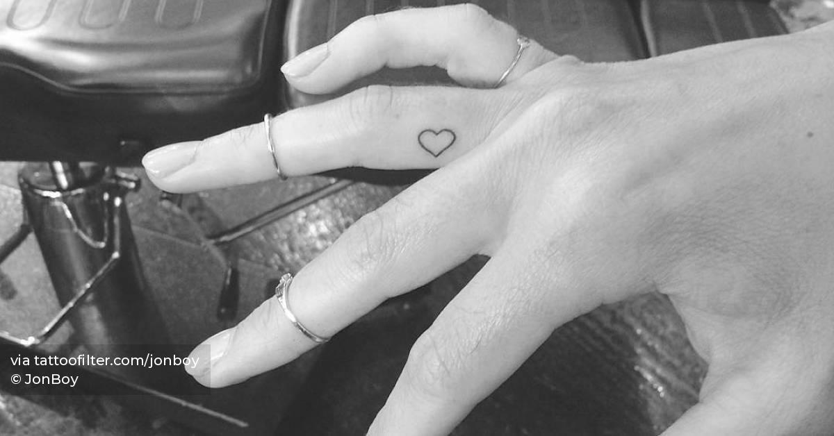 Tiny minimalistic heart tattoo located on the finger.