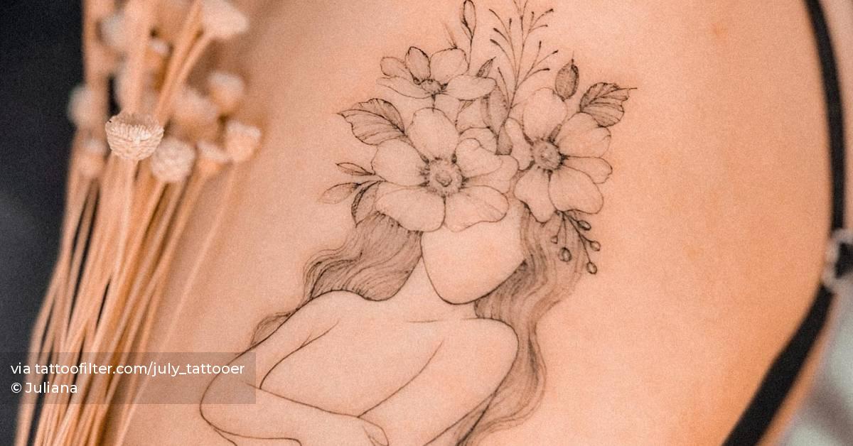 Flower head woman tattoo located on the upper arm.