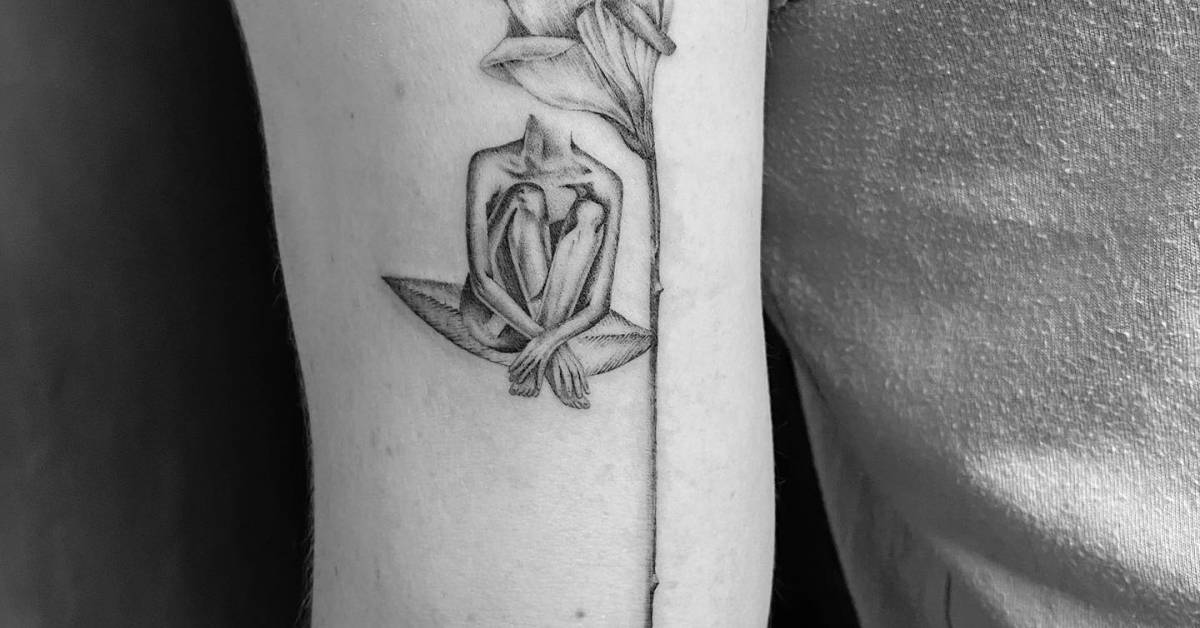 Flower head woman tattoo located on the bicep,