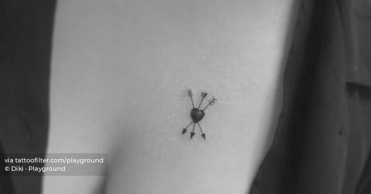 Tiny heart and arrows tattoo placed on the chest.