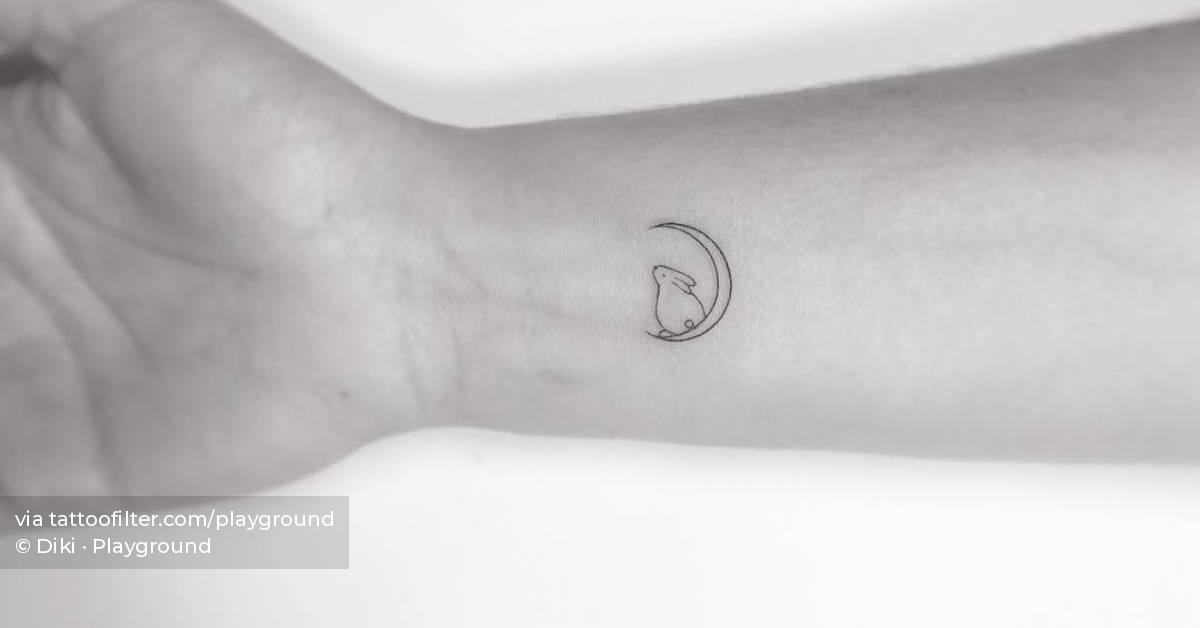 Fine line style rabbit and moon tattooed on the wrist.
