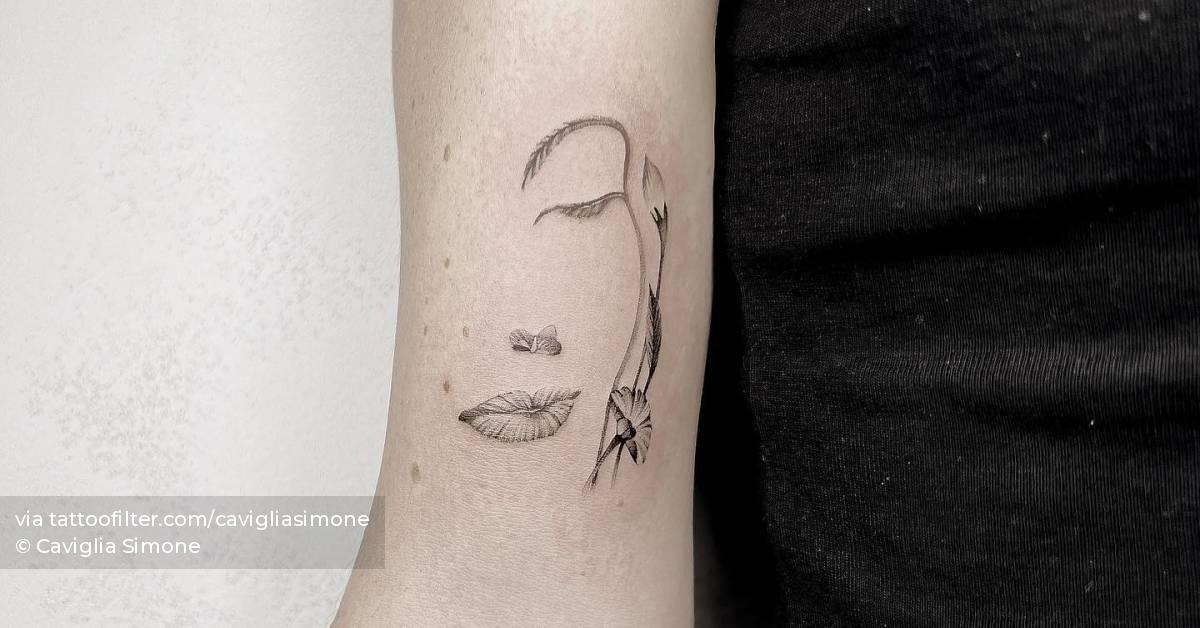 Flower head woman tattoo located on the bicep.