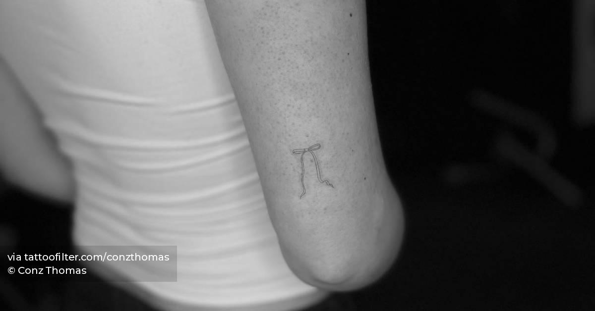 Fine line ribbon tattoo located on the tricep.