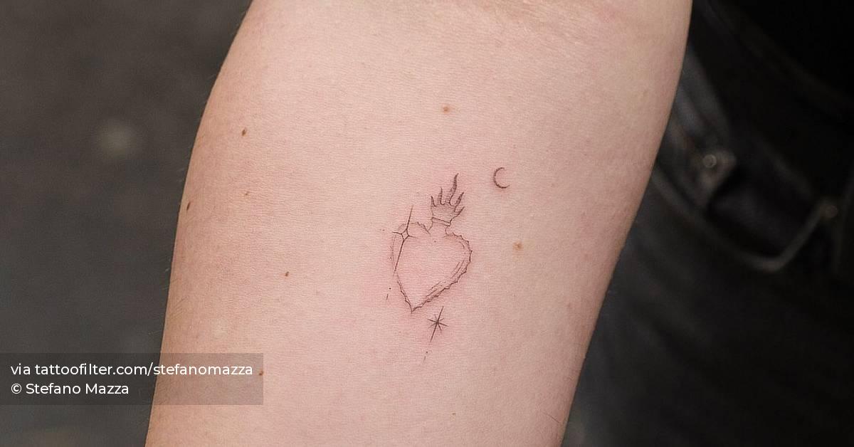 Flaming heart tattoo located on the inner forearm.