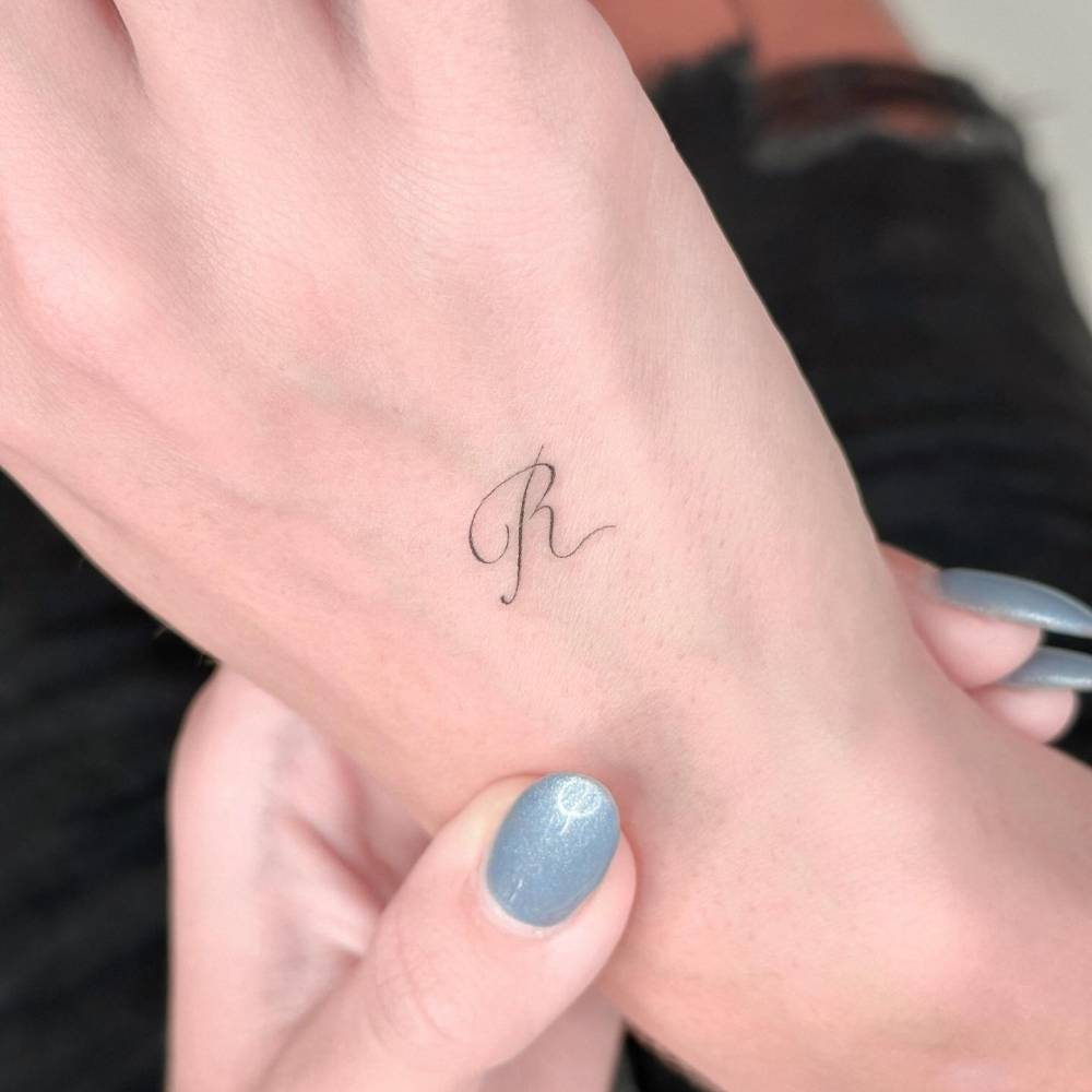 Little Letter R Tattoo Located On The Hand 