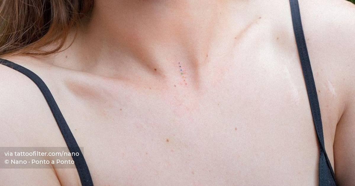 Hand poked rainbow dots tattooed on the collarbone.