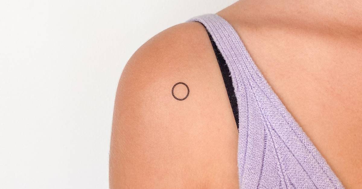 Little circle temporary tattoo located on the shoulder.