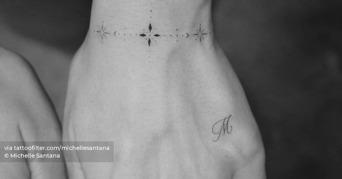 Ornamental wristband and letter "M" tattoos.