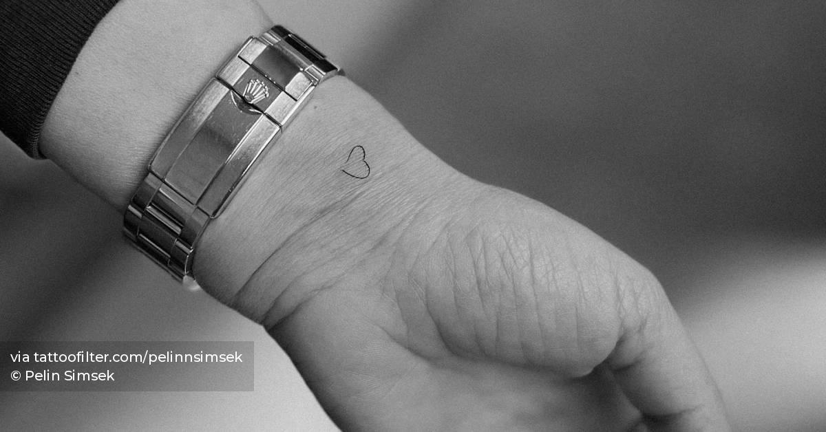 Tiny minimalistic heart tattoo located on the wrist.