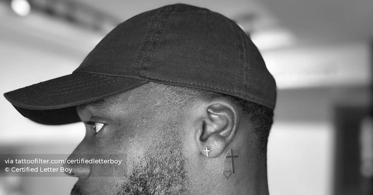 Minimalistic cross and heart tattoo located behind