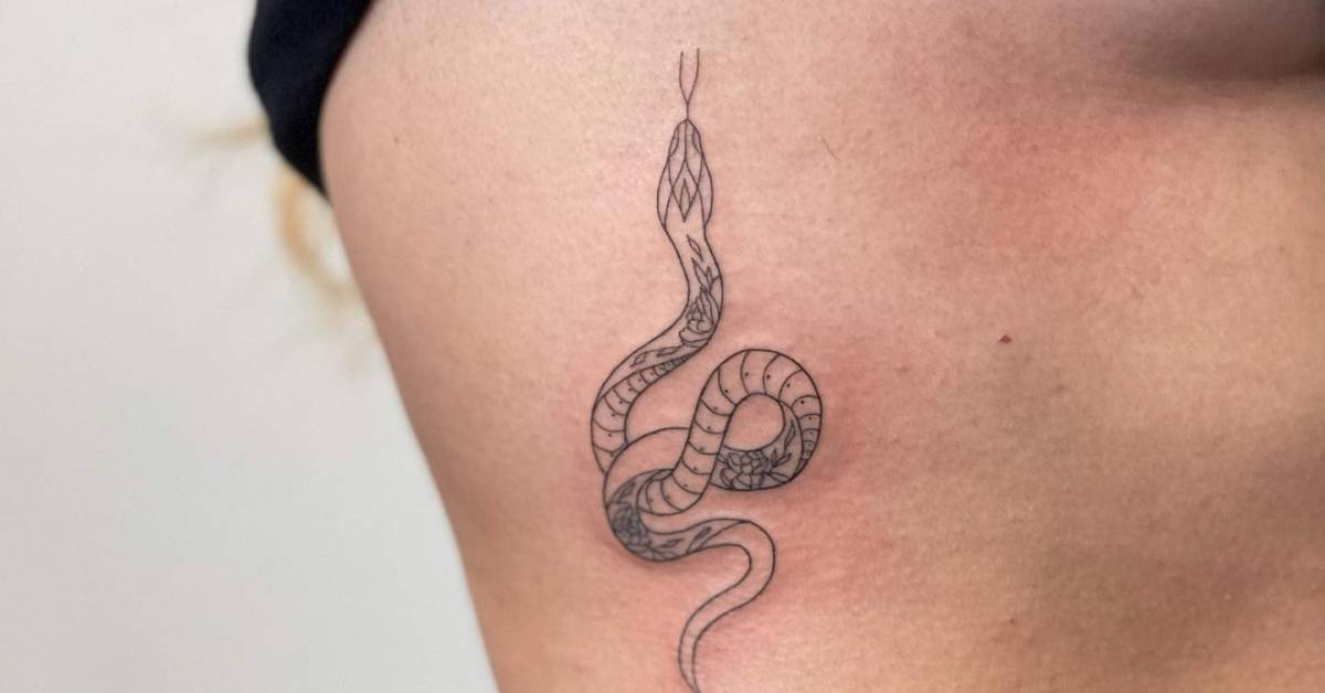 Fine line style snake tattoo located on the rib.