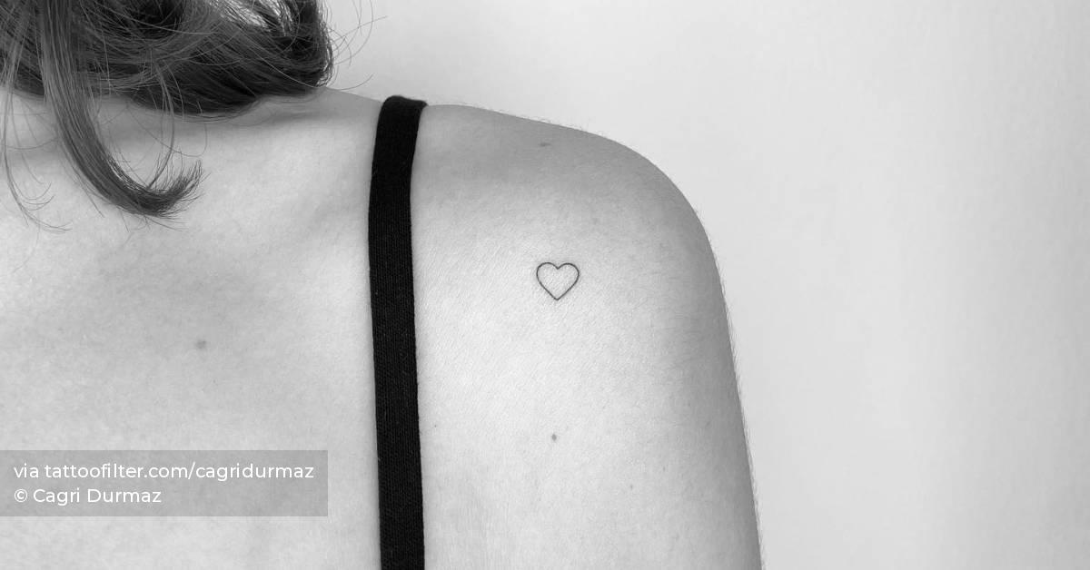 Tiny minimalistic heart tattoo placed on the shoulder.