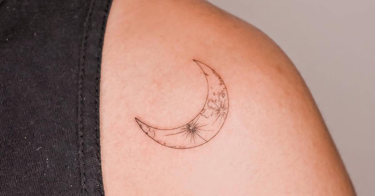 Fine line style crescent moon tattoo placed on the