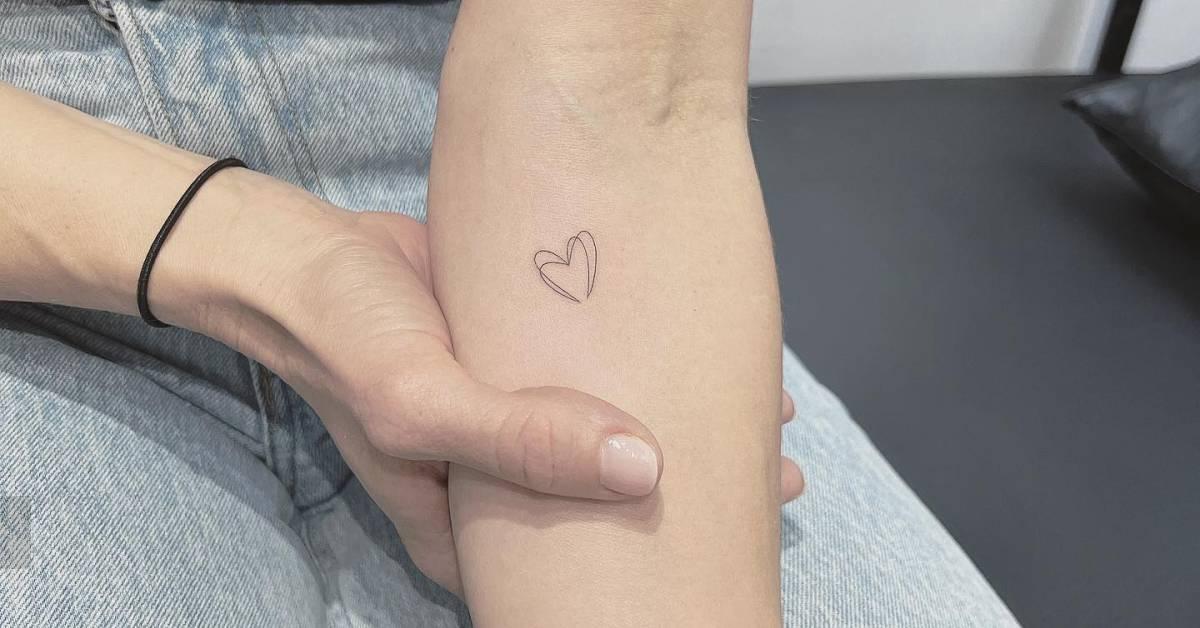 Tiny minimalistic heart tattoo located on the inner