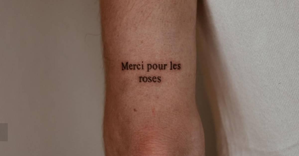 "Merci pour les roses" lettering tattoo placed on the