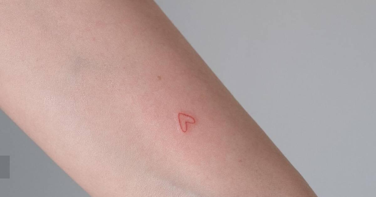 Minimalistic style red heart tattoo located on the