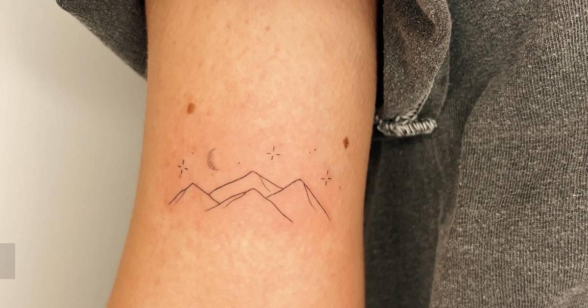 Fine line style mountain tattoo hand poked on the