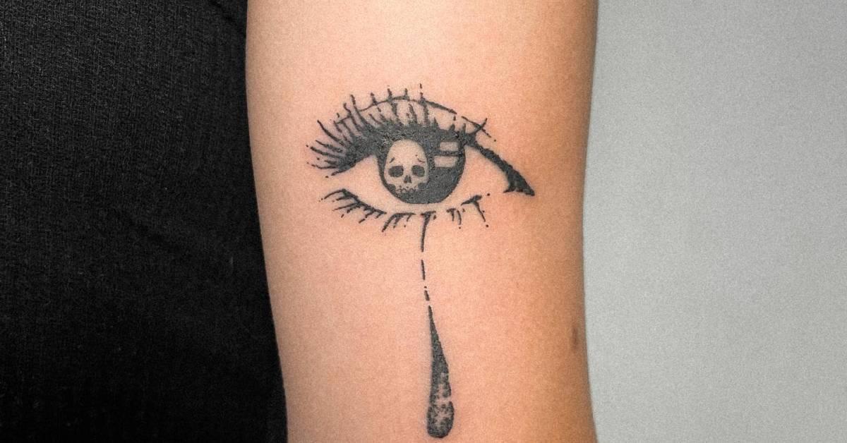 Crying eye tattoo in illustrative style located on the
