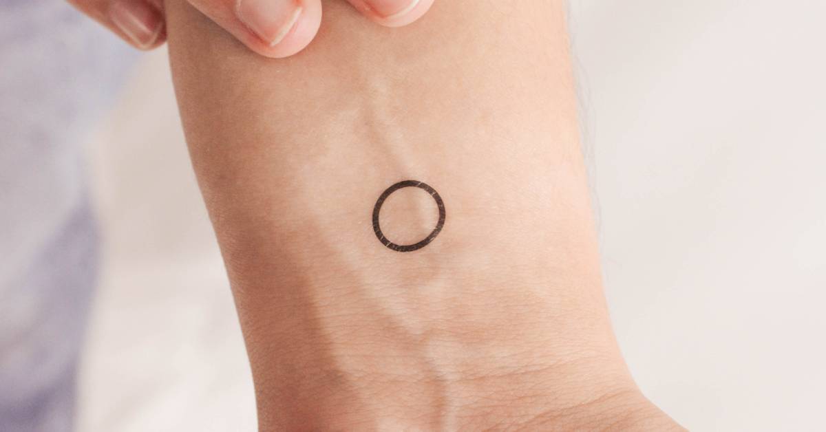 Little circle temporary tattoo located on the wrist.