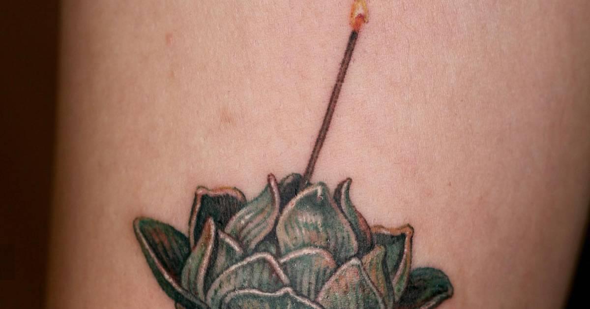 Watercolor style lotus incense tattoo located on the