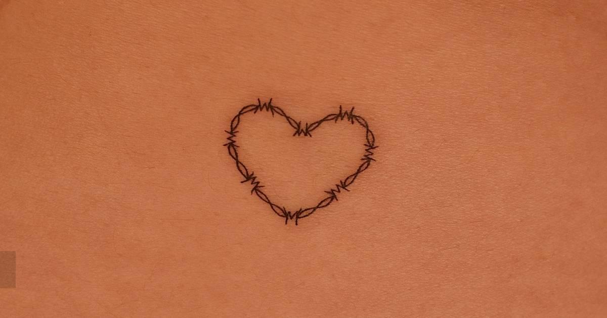Fine line style barbed wire heart tattoo located on the