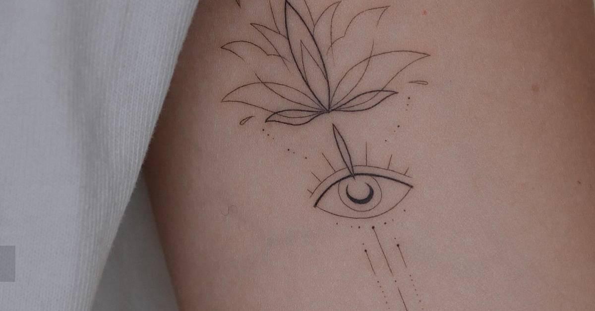 Lotus flower and evil eye tattoo located on the inner