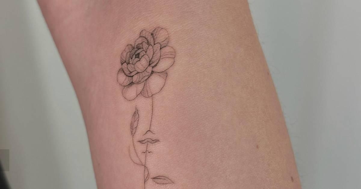 Single needle flower head woman tattoo located on the