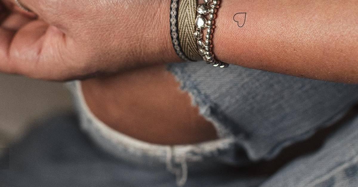 Tiny minimalistic heart tattoo located on the wrist.