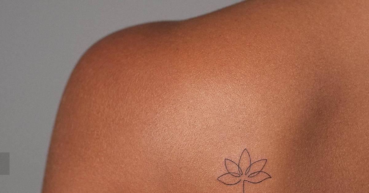 Lotus flower tattoo in fine line style located on the