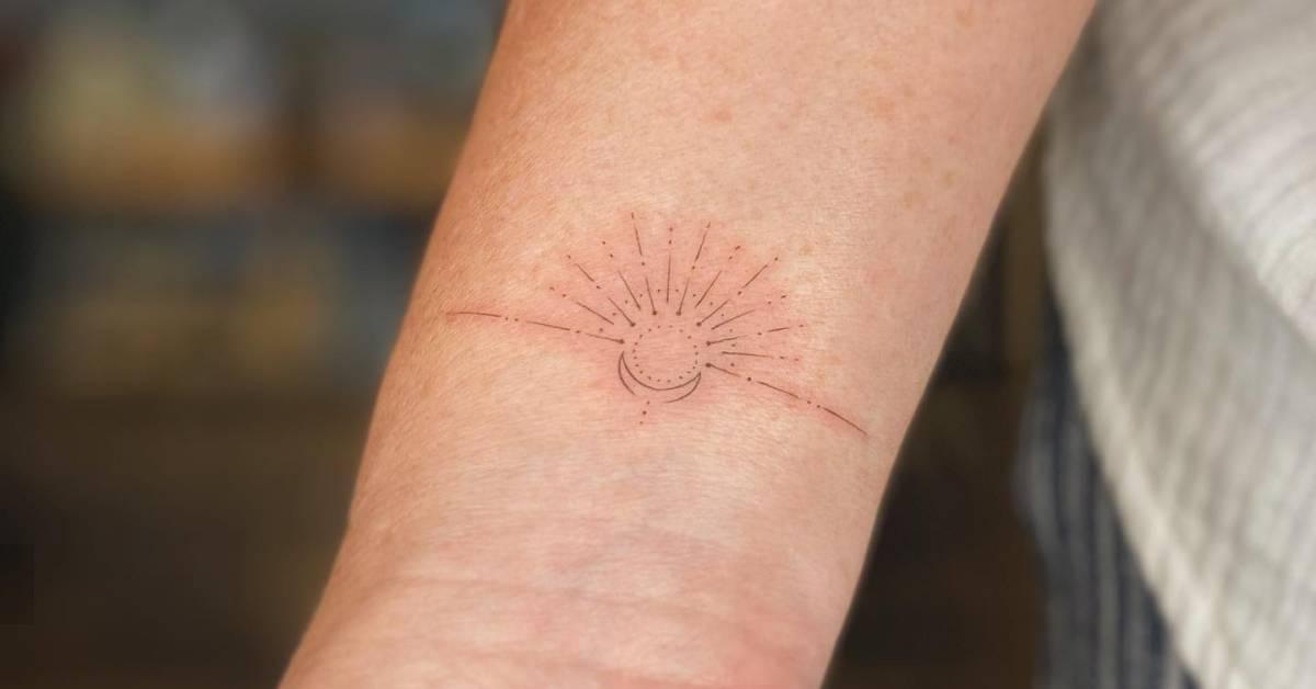 Fine line style sun and moon tattoo located on the