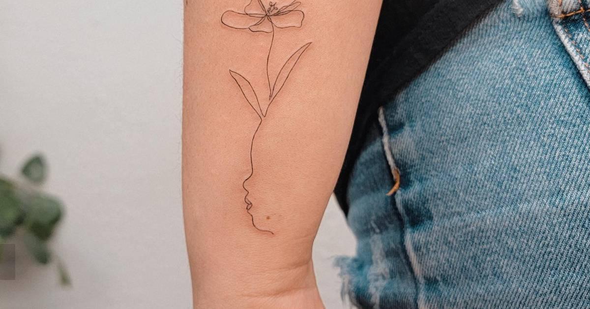 Fine line style flower head woman tattoo placed on the