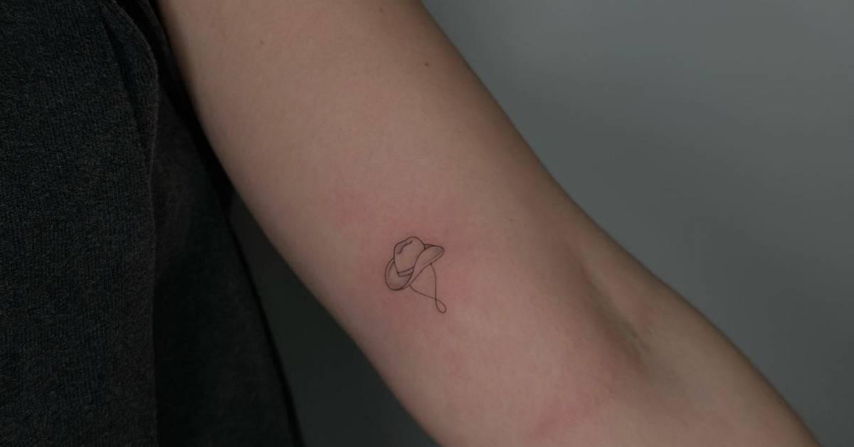 Fine line style tiny cowboy hat tattoo located on the