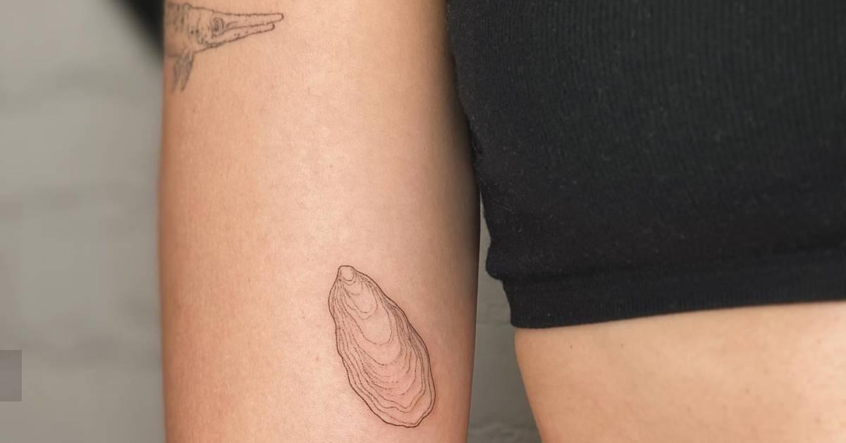Fine line style oyster tattoo located on the inner arm.
