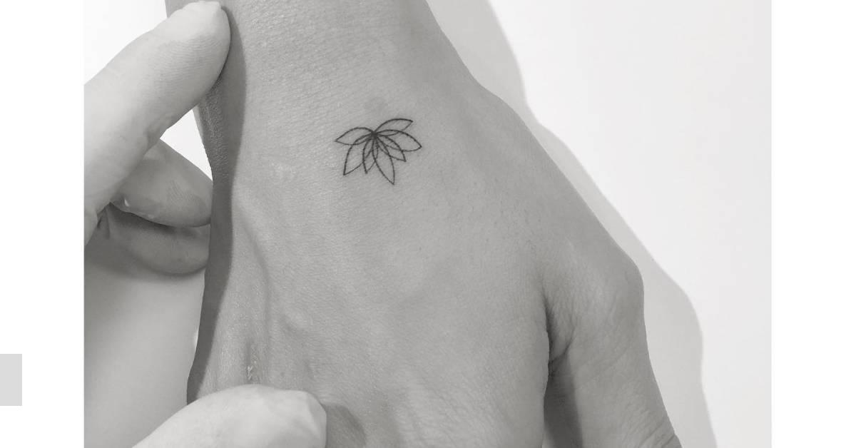 Tiny fine line lotus flower tattoo located on the