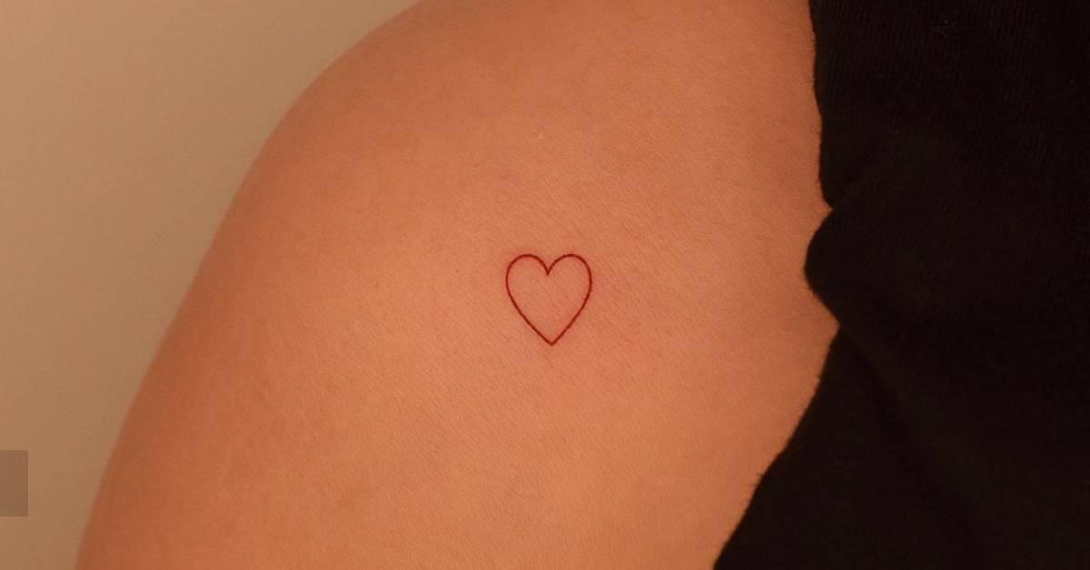 Minimalistic red heart tattoo located on the shoulder.