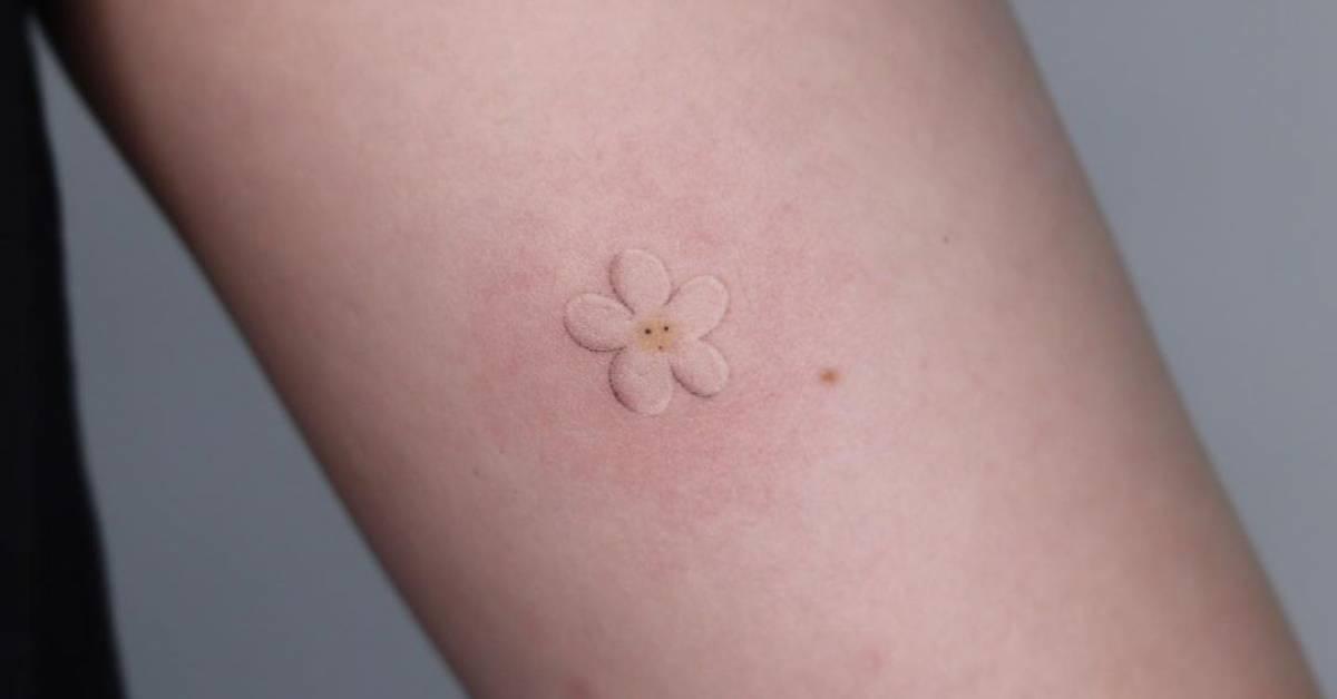 Hand poked daisy flower tattoo located on the tricep.