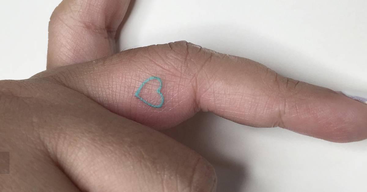 Minimalistic style blue heart tattoo located on the