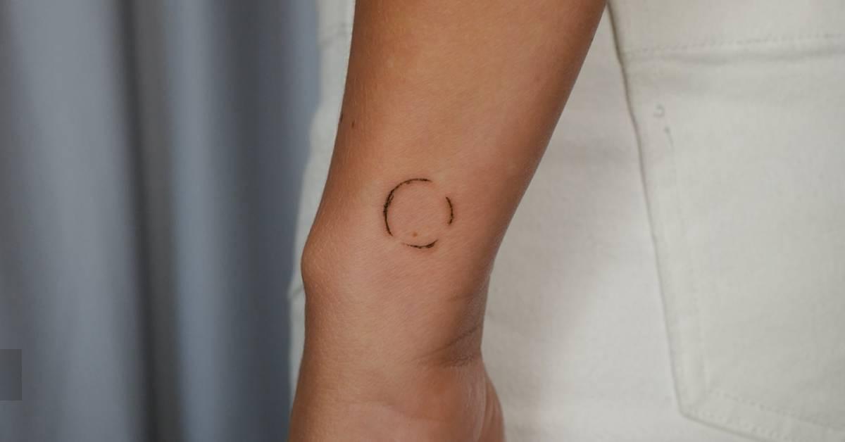 Minimalistic style circle tattoo located on the wrist.