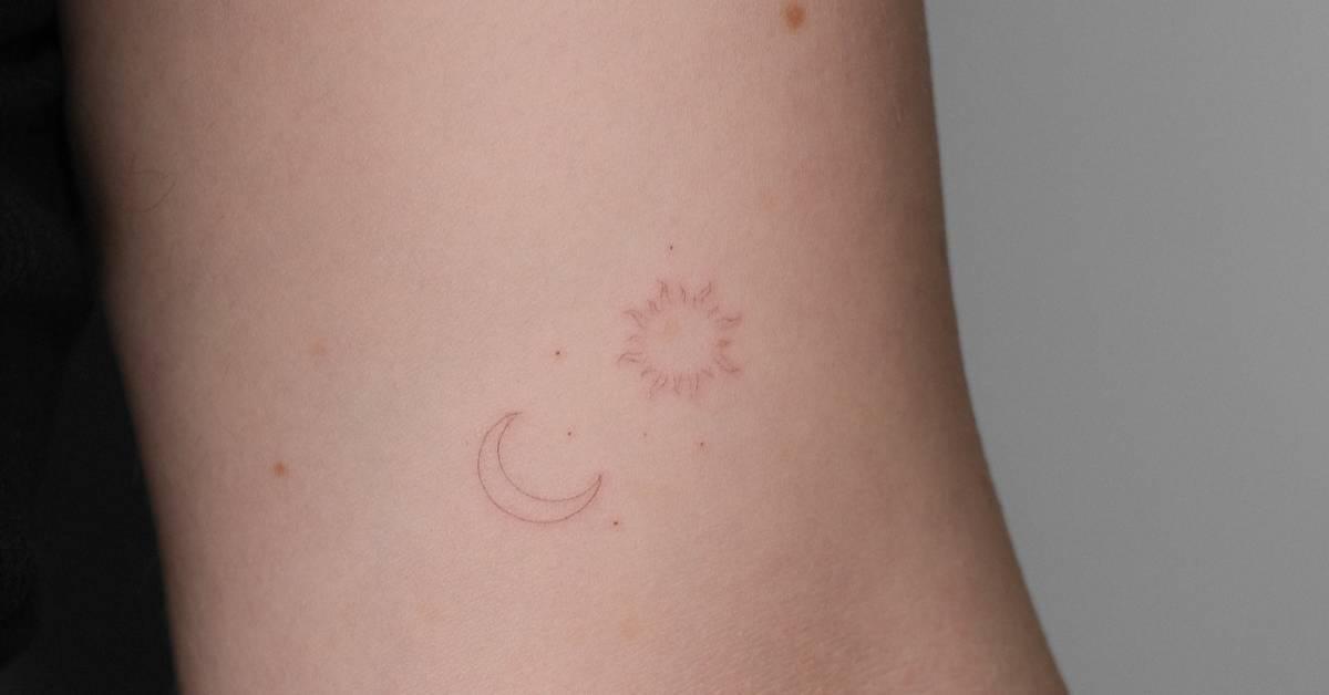 Fine line style sun and moon tattoo located on the