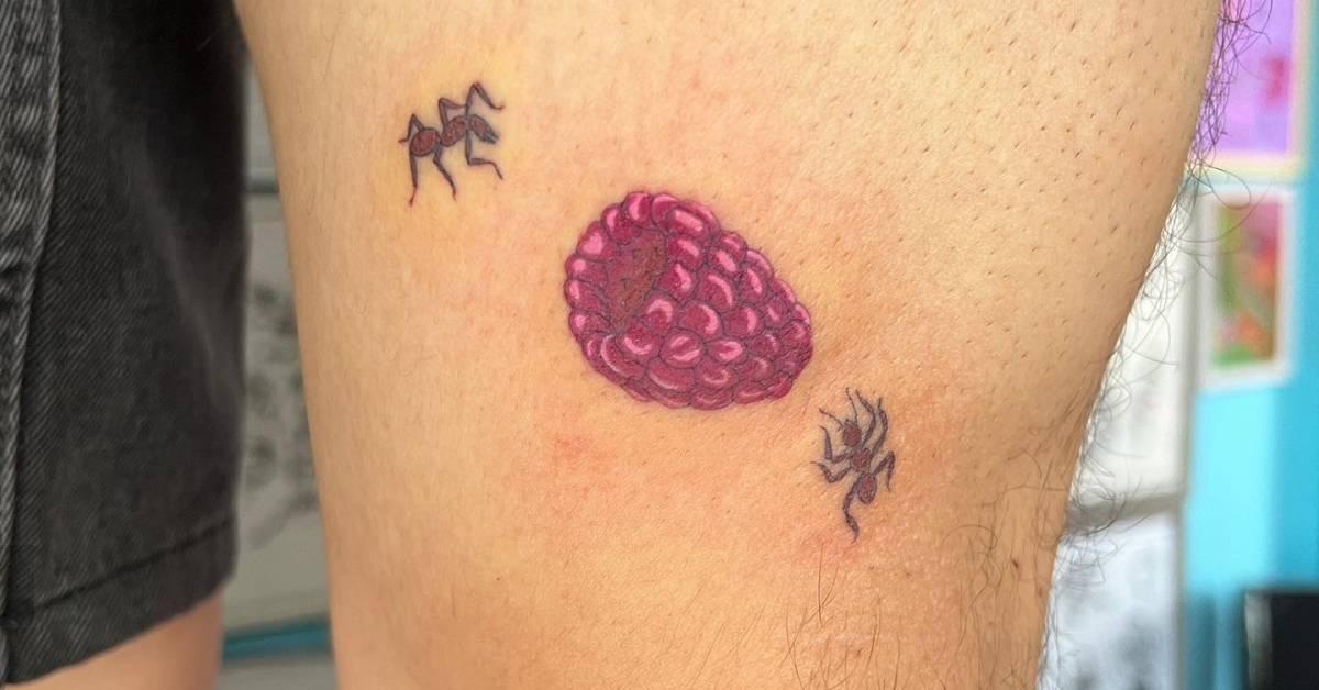 Ants and raspberry tattoo located on the thigh,