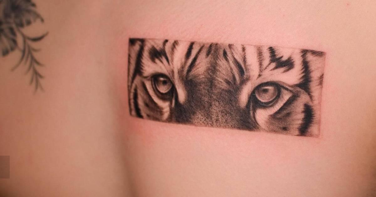 Black and grey tiger eye tattoo located on the chest.