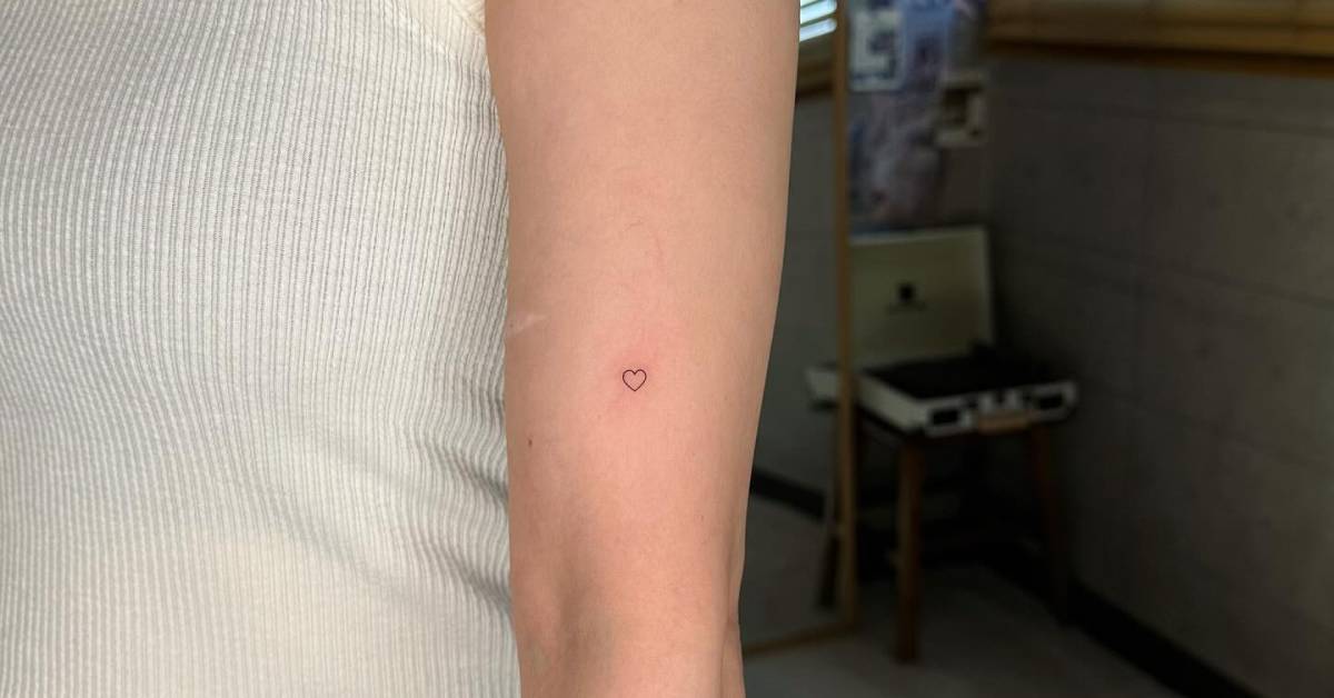 Tiny minimalistic heart tattoo hand poked on the upper
