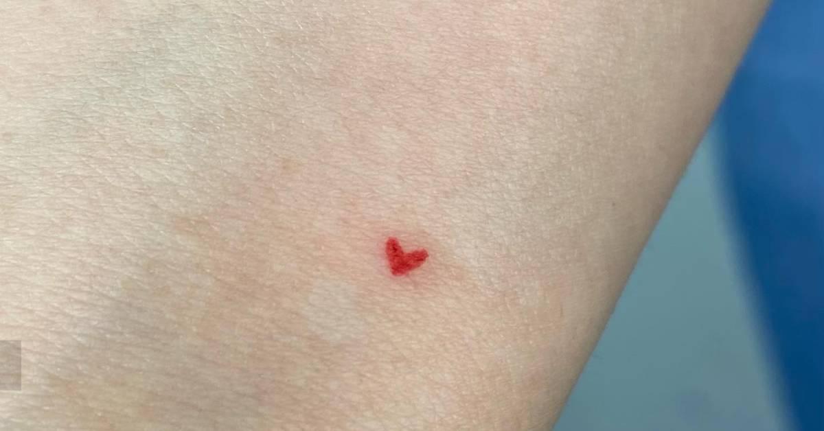 Minimalistic little red heart tattoo placed on the